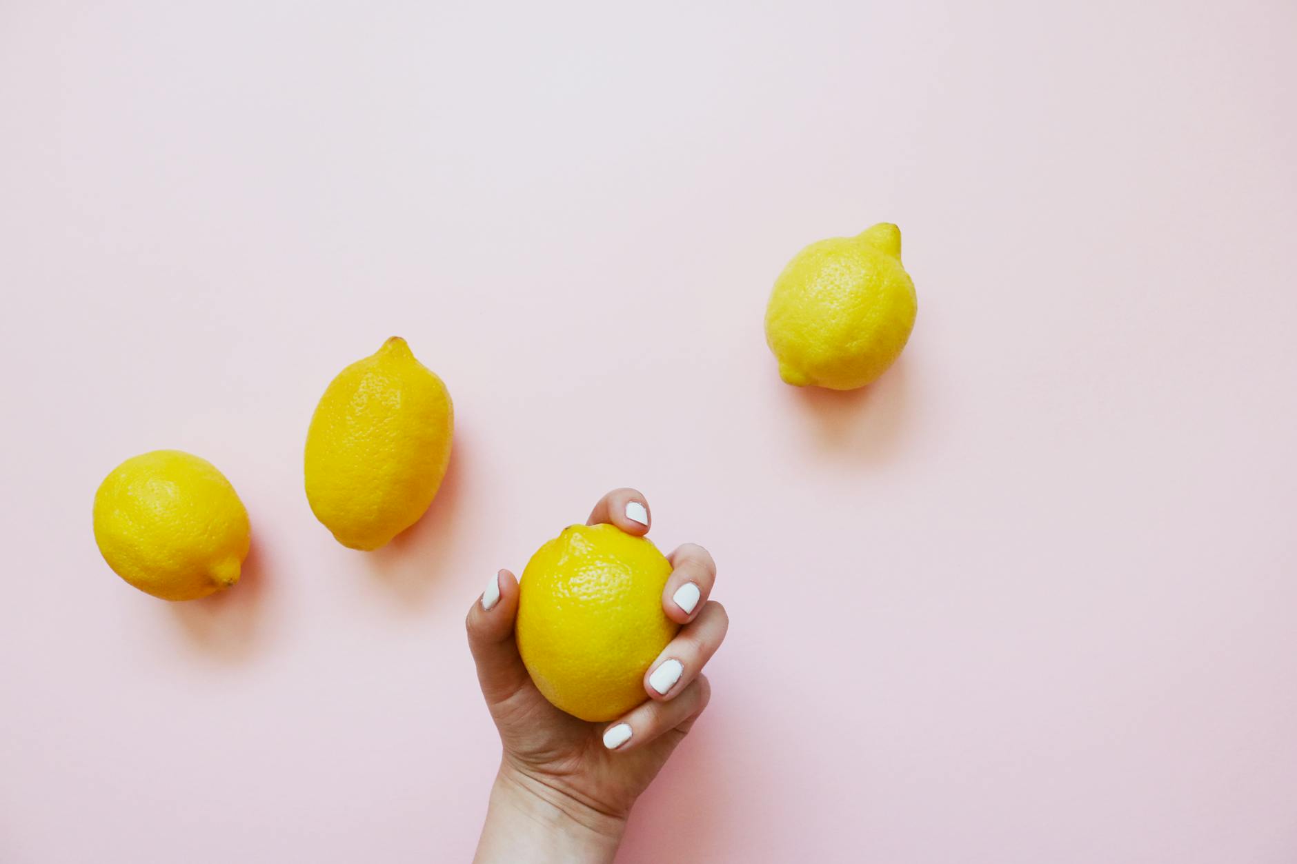 Close-up of a hand holding an orange vibrator against a minimalistic purple backdrop, showcasing modern sensuality.