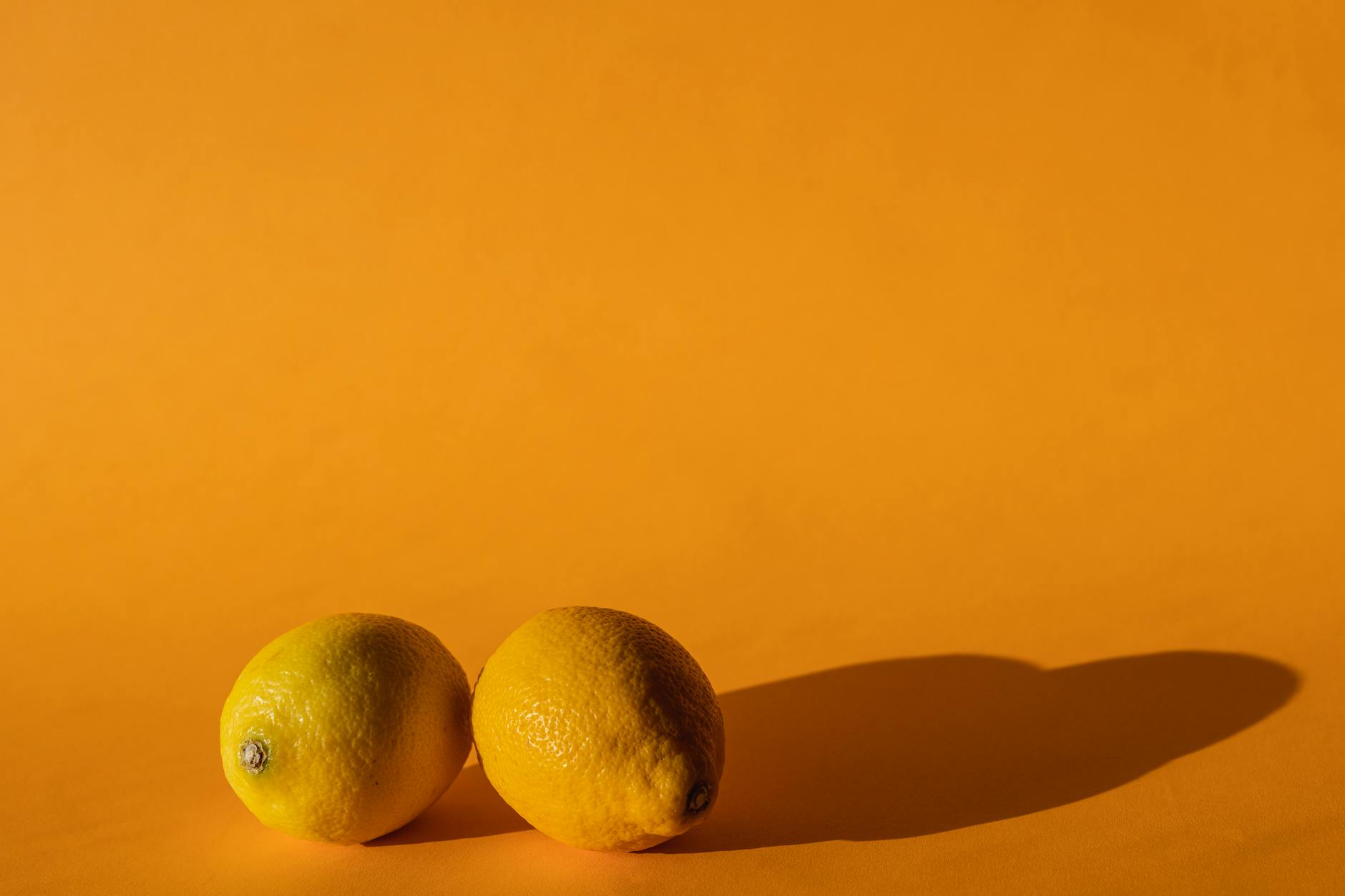 Yellow silicone vibrator surrounded by fresh fruit on vibrant background